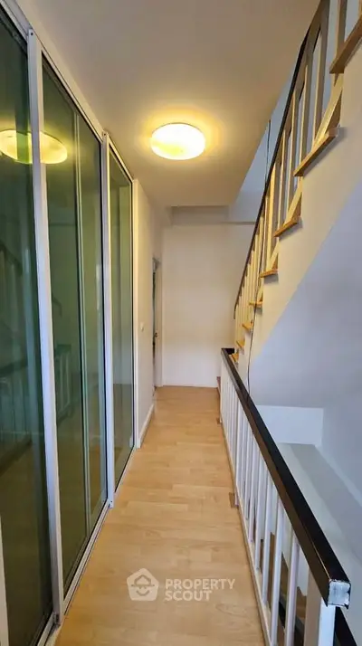 Modern hallway with wooden flooring and glass sliding doors in a stylish home.