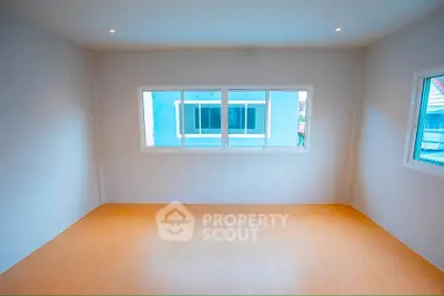 Spacious empty room with large windows and wooden flooring, ideal for customization.