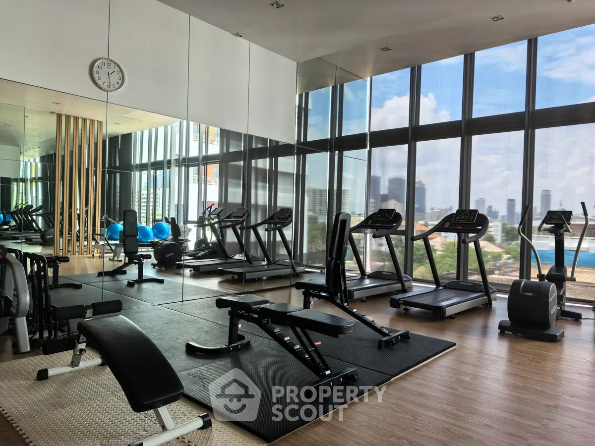 Spacious modern gym with city view, featuring treadmills and fitness equipment.