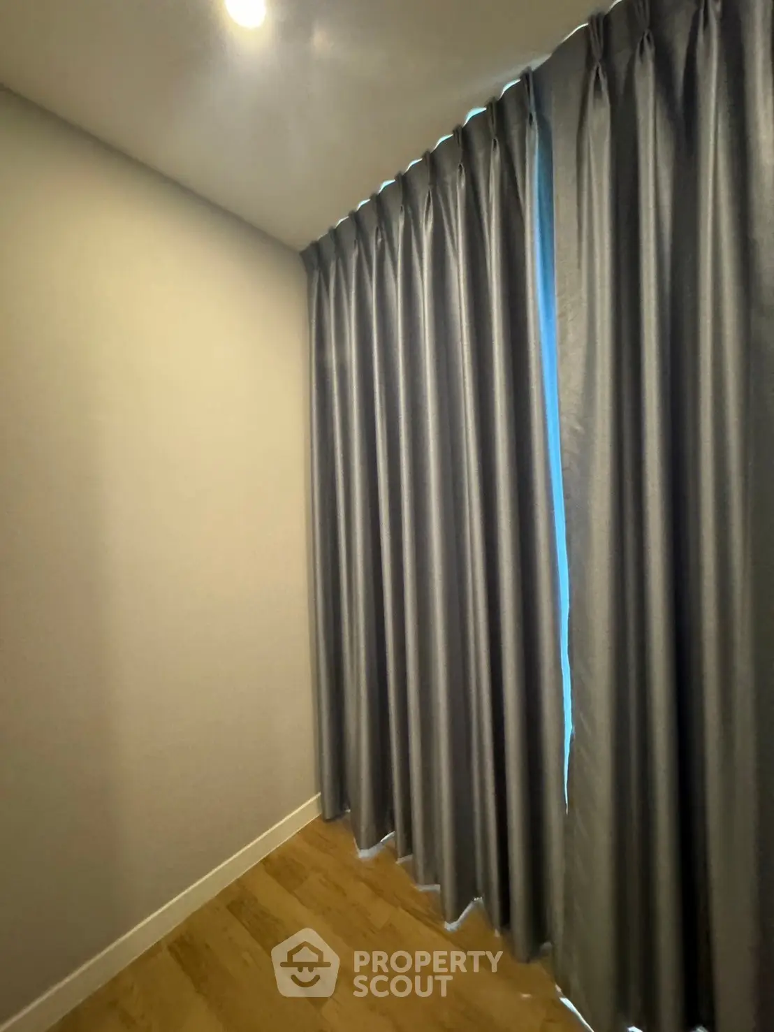 Cozy corner with elegant floor-to-ceiling curtains and warm wooden flooring.