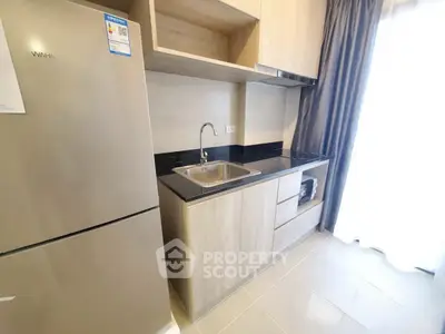 Modern kitchen with sleek design, featuring a stainless steel fridge and elegant cabinetry.