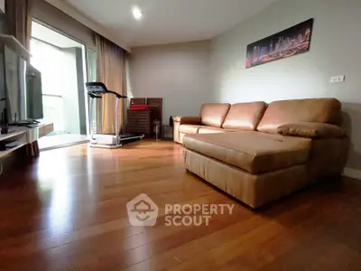 Spacious living room with hardwood floors and cozy leather sofa