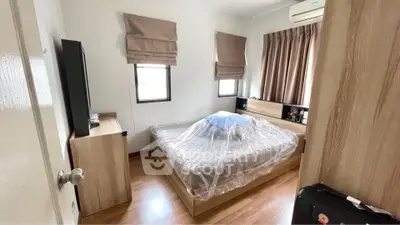 Cozy bedroom with wooden flooring and modern furnishings, featuring a large bed and ample natural light.