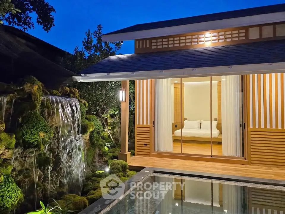 Luxurious Japanese-style villa with serene waterfall and private pool at dusk.