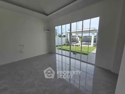 Spacious empty room with large glass doors opening to a lush garden view.