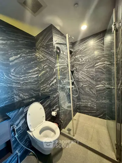 Luxurious modern bathroom with sleek marble walls and glass shower enclosure.