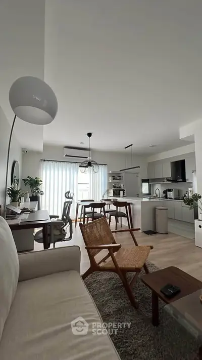 Spacious modern living room with open kitchen, stylish furniture, and natural light.