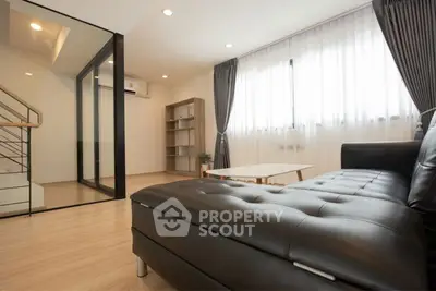 Modern living room with sleek black leather sofa and natural light