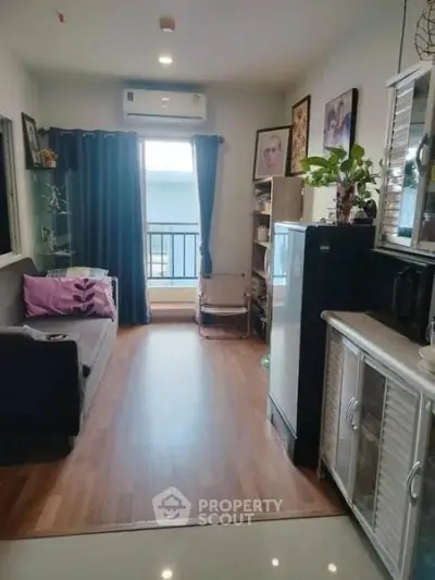 Cozy living room with wooden flooring, modern decor, and ample natural light from large window.