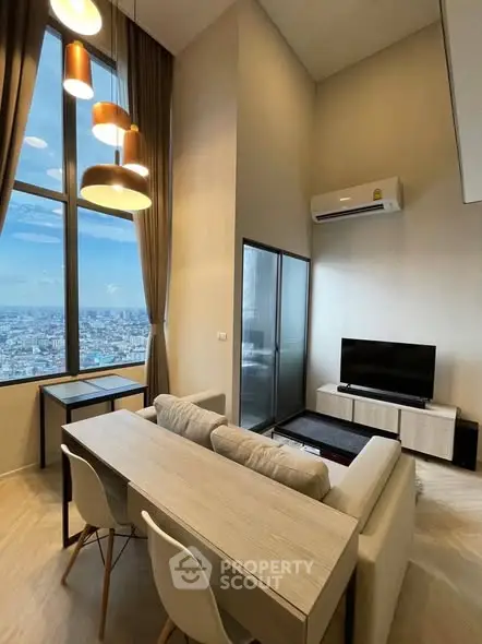 Modern living room with high ceilings and city view, featuring stylish furniture and large windows.