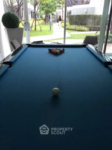 Luxurious common area with pool table and garden view in modern residential complex.
