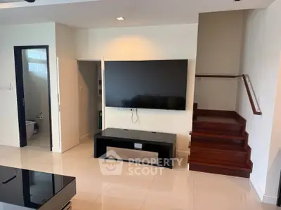 Modern living room with sleek TV setup and elegant staircase