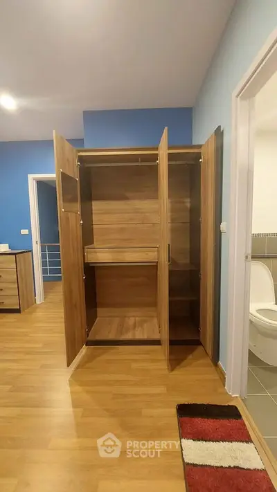 Spacious bedroom with open wooden wardrobe and adjacent bathroom