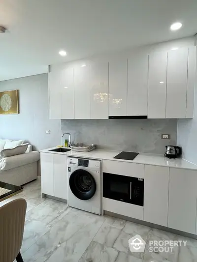 Modern kitchen with sleek white cabinets and built-in appliances in open layout