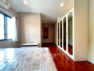 Spacious bedroom with hardwood floors and mirrored closet doors in modern apartment.
