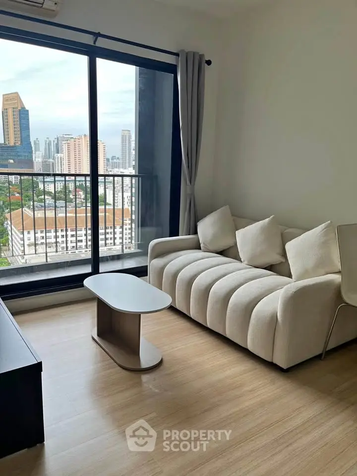 Modern living room with city view, featuring a stylish sofa and sleek coffee table.