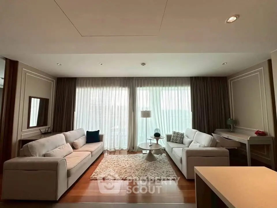 Spacious living room with elegant decor and large windows offering natural light.