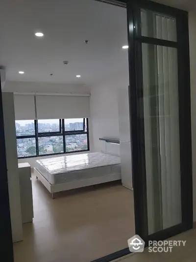 Modern bedroom with large windows offering city views in a high-rise apartment.