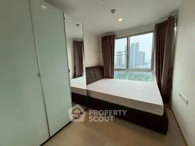 Modern bedroom with city view, featuring sleek wardrobe and large window for natural light.