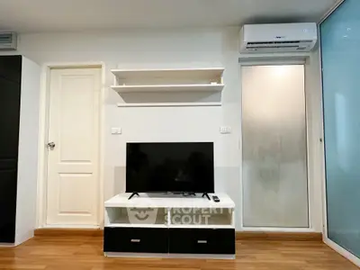 Modern living room with sleek TV setup and air conditioning, featuring minimalist design and wooden flooring.