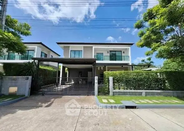 Modern two-story house with lush greenery and gated entrance