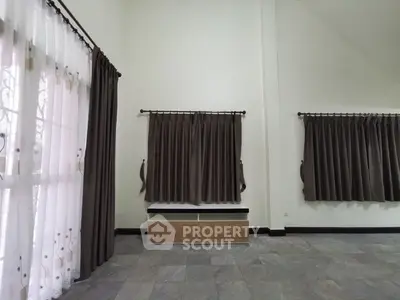 Spacious living room with high ceilings, elegant dark curtains, and ample natural light, perfect for a modern lifestyle.