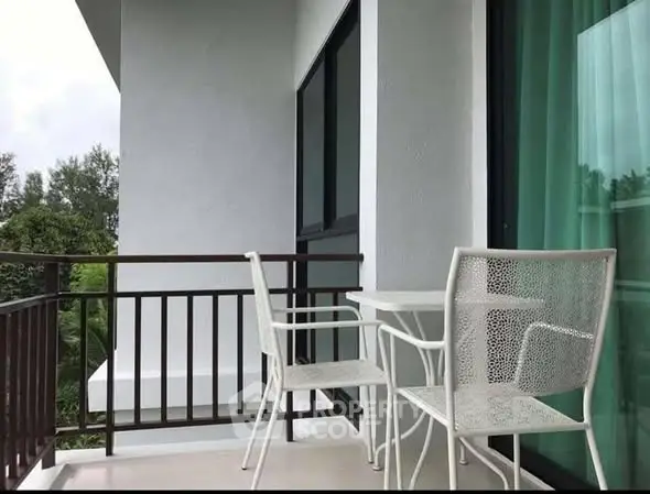 Charming balcony with modern white furniture and lush green view, perfect for relaxation.