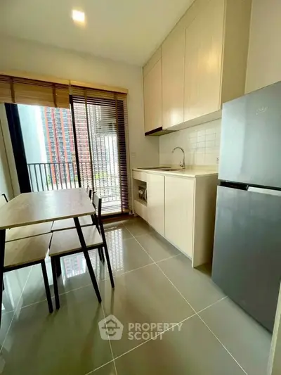 Modern kitchen with sleek cabinetry, dining table, and balcony view in a stylish apartment.