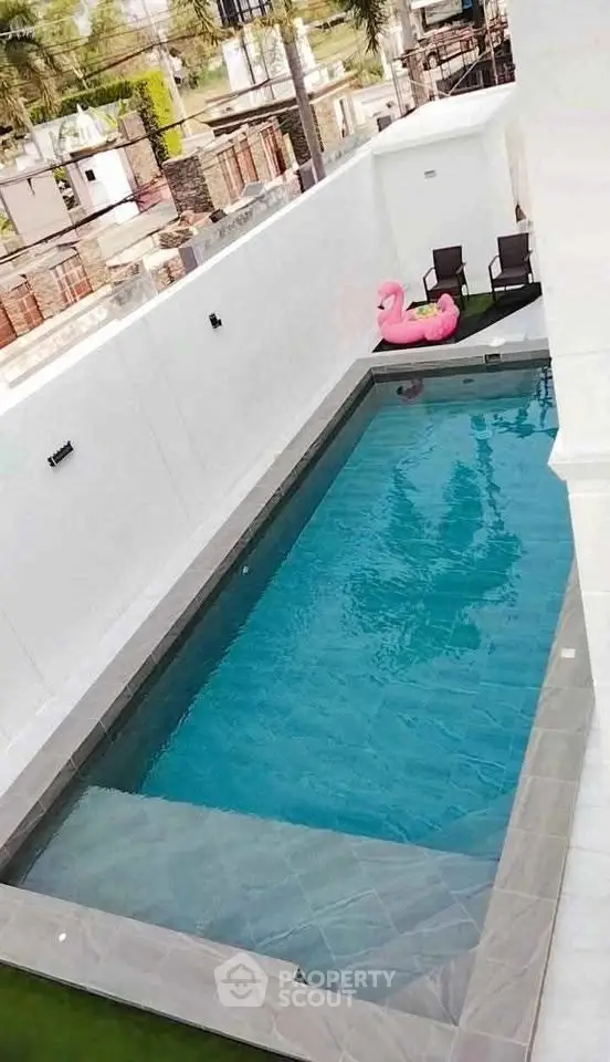 Luxurious private pool with stylish seating and inflatable flamingo, perfect for relaxation and entertainment.