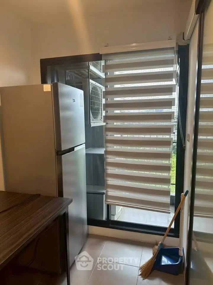 Modern kitchen with sleek fridge and large window blinds, offering a bright and airy atmosphere.