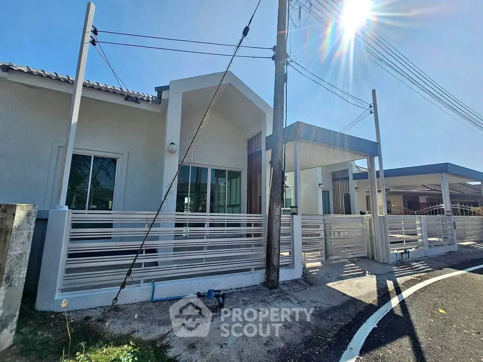 Modern single-story house with sleek fence and driveway in sunny neighborhood.
