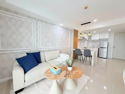 Modern living room with stylish decor and open kitchen layout, featuring elegant furniture and bright lighting.