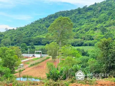 Scenic land plot with lush greenery and mountain backdrop, ideal for development or investment.