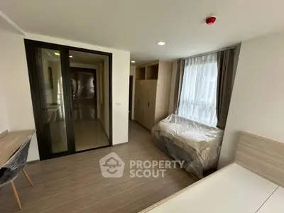 Modern bedroom with wooden flooring and large window for natural light