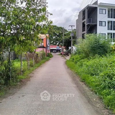 Charming residential street with lush greenery and modern apartment building.