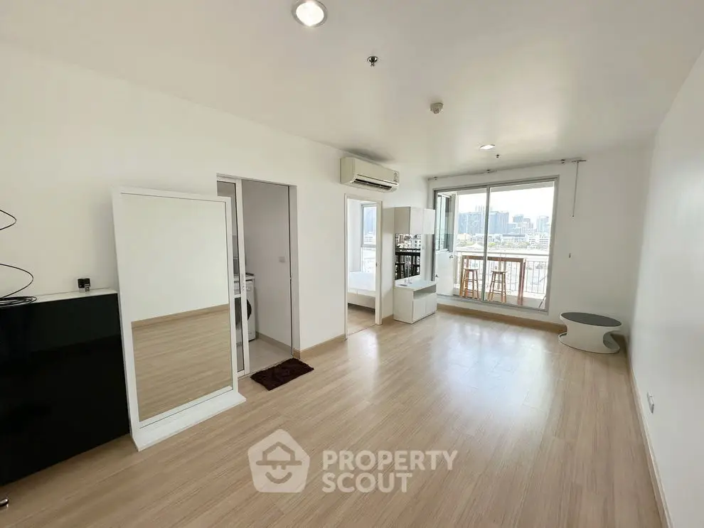 Spacious modern living room with balcony and city view, featuring sleek wooden flooring.