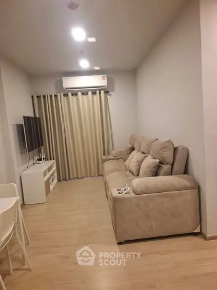 Modern living room with cozy beige sofa and wall-mounted TV in a stylish apartment.