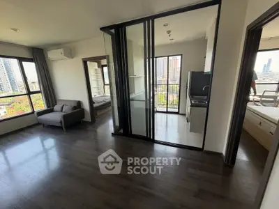 Modern apartment with open layout, large windows, and city views, featuring a sleek kitchen and cozy living area.
