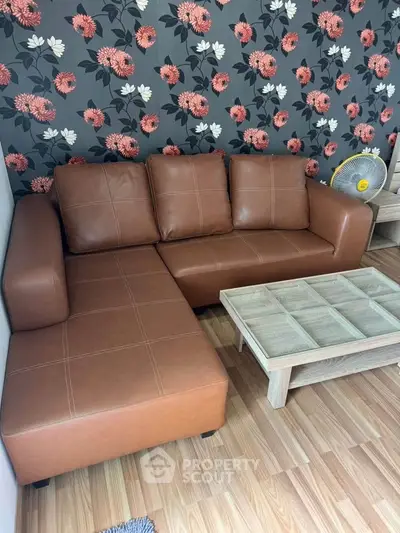 Stylish living room with brown leather sofa and floral wallpaper, perfect for modern comfort.