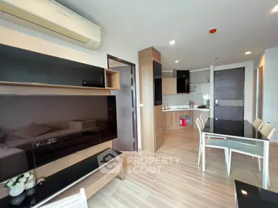 Modern open-plan living room and kitchen with sleek furniture and wooden flooring