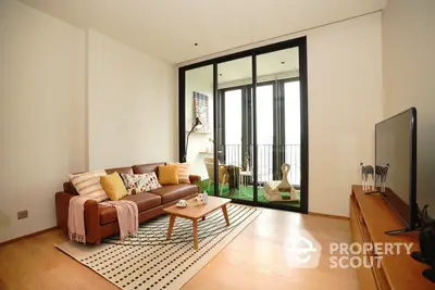 Spacious living room with large windows leading to a cozy balcony, modern furniture, and elegant wooden flooring, perfect for urban living.