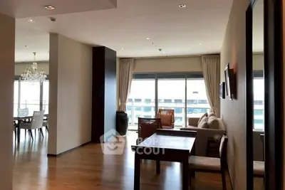Spacious modern living room with elegant dining area and large windows offering city views.
