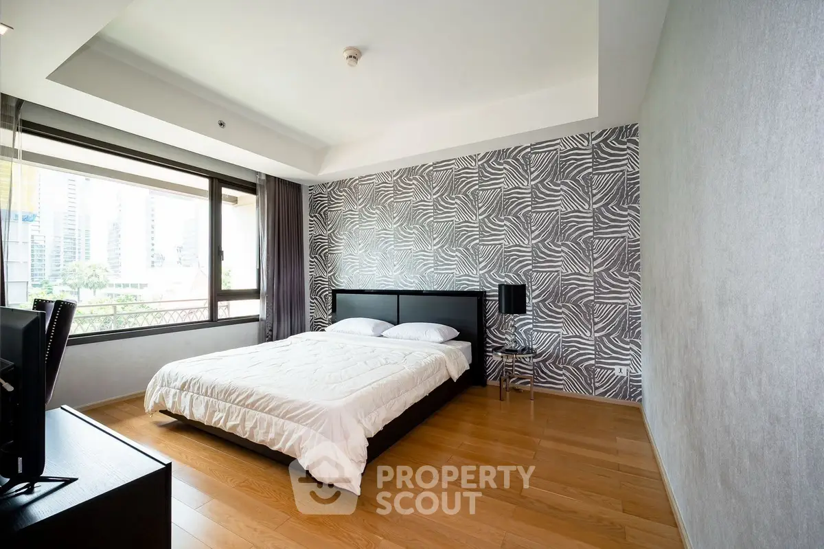 Modern bedroom with large window and stylish wallpaper, featuring wooden flooring and contemporary decor.