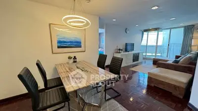 Modern living room with stylish dining area and elegant lighting, featuring a cozy sofa and large window view.