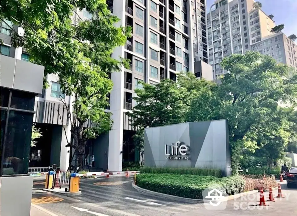 Modern high-rise condominium building with lush greenery and secure entrance