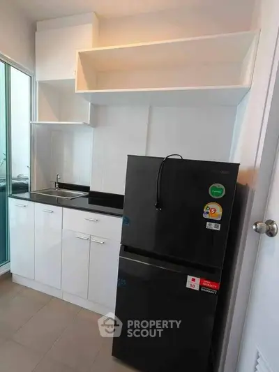 Modern kitchen with sleek black fridge and white cabinetry, perfect for contemporary living.