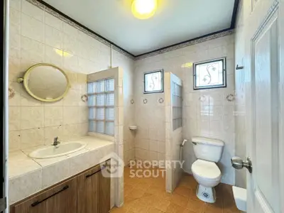 Spacious bathroom with tiled walls and modern fixtures in a real estate property.