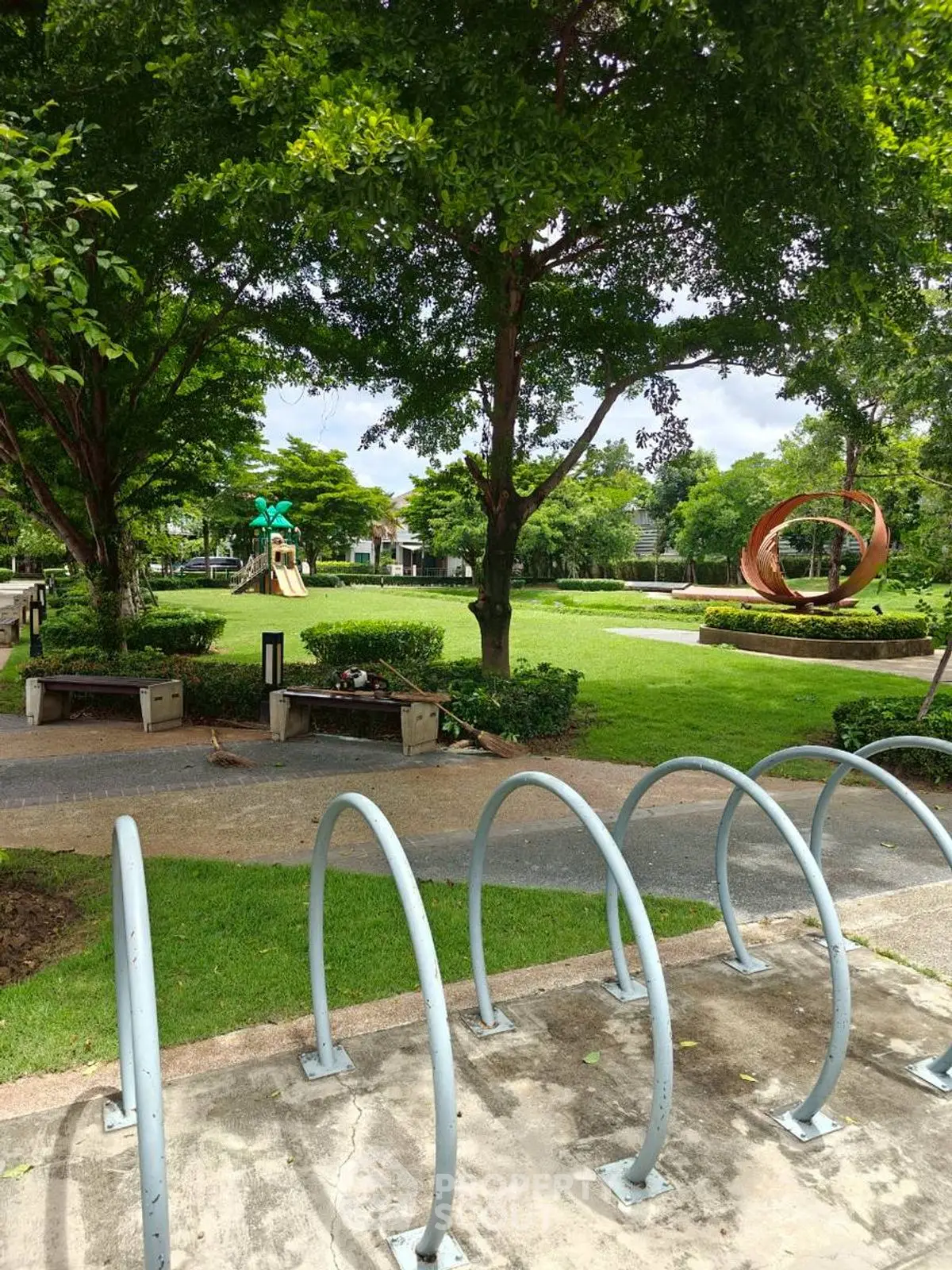 Lush green garden with sculptures and bike racks in a serene residential area.