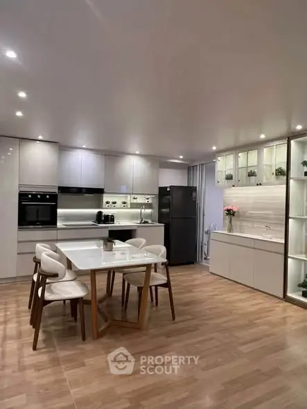 Modern kitchen with sleek cabinetry, dining table, and built-in appliances in a stylish open layout.