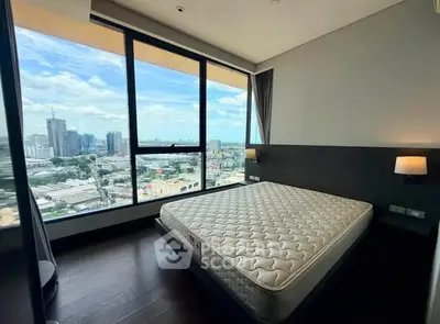 Spacious bedroom with stunning city view from large windows in modern high-rise apartment.